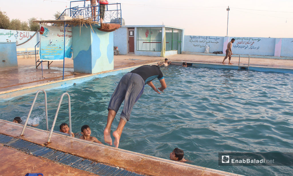 A man jumping into the water in the "al-Iradeh" swimming pool in Killi town in northern Idlib countryside – September 2020 (Enab Baladi / Iyad Abdel Jawad)
