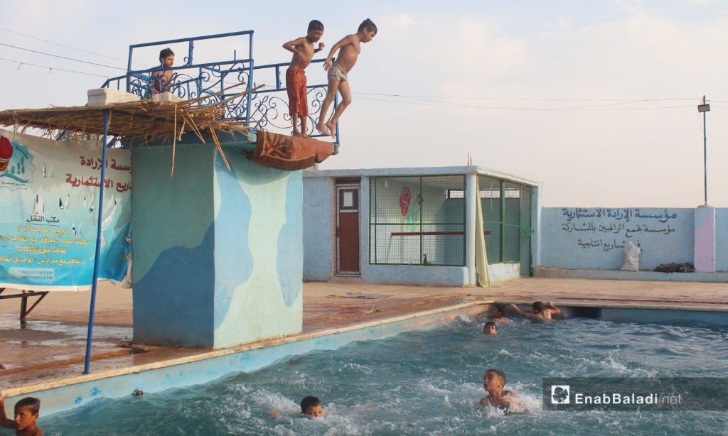 Children preparing to jump into the water in the "al-Iradeh" swimming pool in Killi town in northern Idlib countryside – September 2020 (Enab Baladi / Iyad Abdel Jawad)