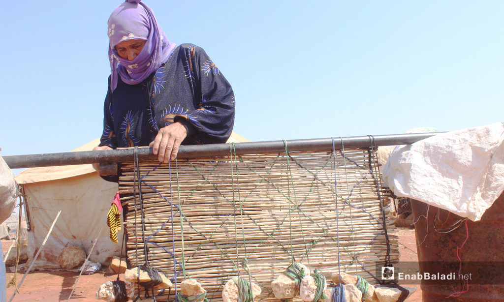 Um Mohammed while making mats that are locally known as “al-Zarb” after combining “al-Zal” cane sticks together – 28 August 2020 (Enab Baladi / Iyad Abdel Jawad)