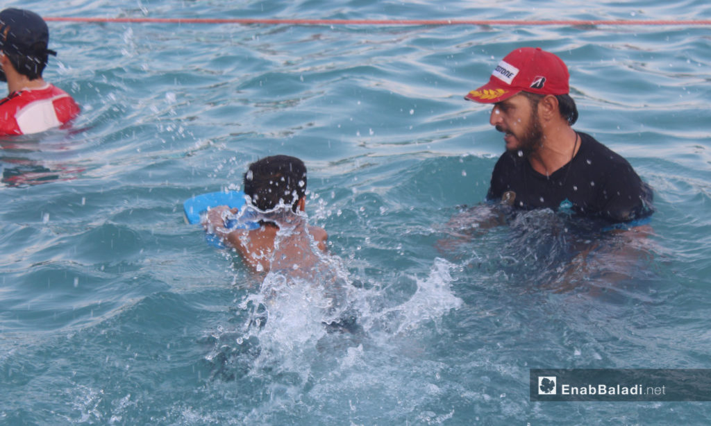 A swimming coach teaching a child how to swim- September 2020 (Enab Baladi / Iyad Abdel Jawad)