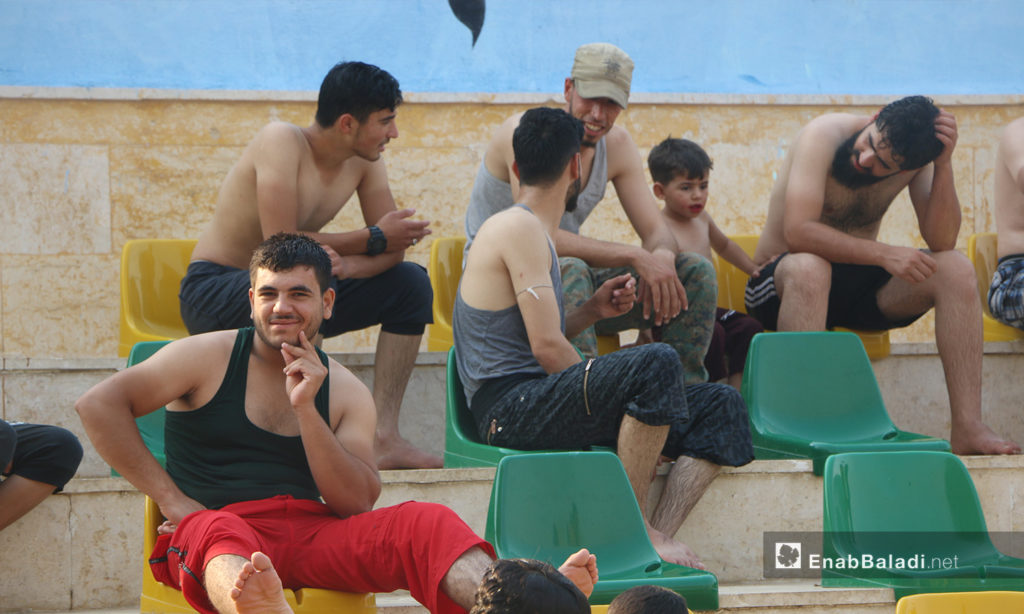 A group of young men sitting beside the swimming pool in Idlib – September 2020 (Enab Baladi / Anas al-Khouli)