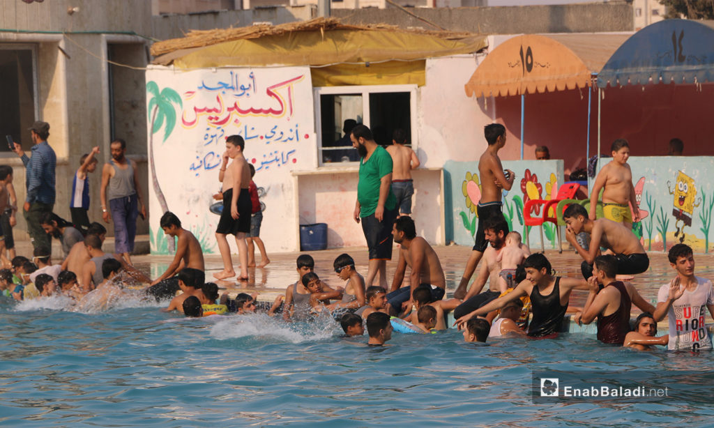 A group of men and children at Idlib’s municipal swimming pool - September 2020 (Enab Baladi / Anas al-Khouli)