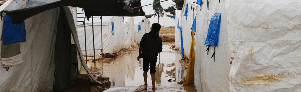 Caption 1: A child wading in the water that flooded the Falah camp in the northern countryside of Aleppo, which lacks adequate equipment for facing winter rains - 4 November 2020 (Enab Baladi - Abdul al-Salam Majaan)