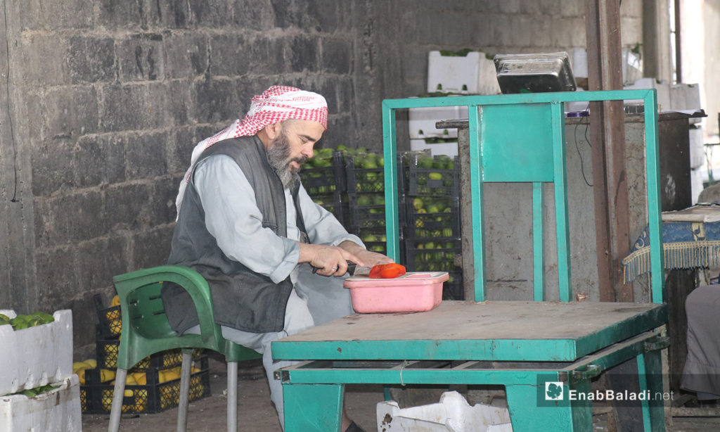 A man cutting vegetables in al-Hal street market in al-Raqqa city - September 2020 (Enab Baladi - Abdul Aziz al-Saleh)