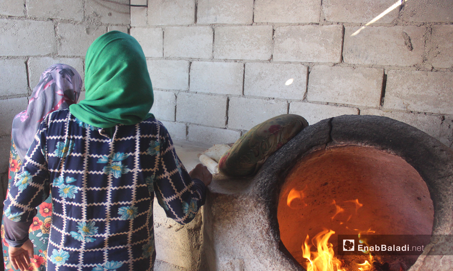 Women baking flatbreads in a tandoor oven  in the village of killi in the northern countryside of Idlib - October 2020 ((Enab Baladi / Iyad Abdel Jawad) )