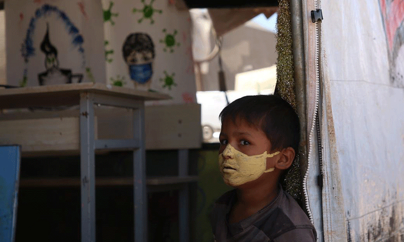 A child with a protective mask against the novel coronavirus painted on his face in the “al-Anwar” displacement camp, west of Maraat Misrin, northwestern Syria-  16 September 2020 (AFP/ Muhammad al-Rifai)