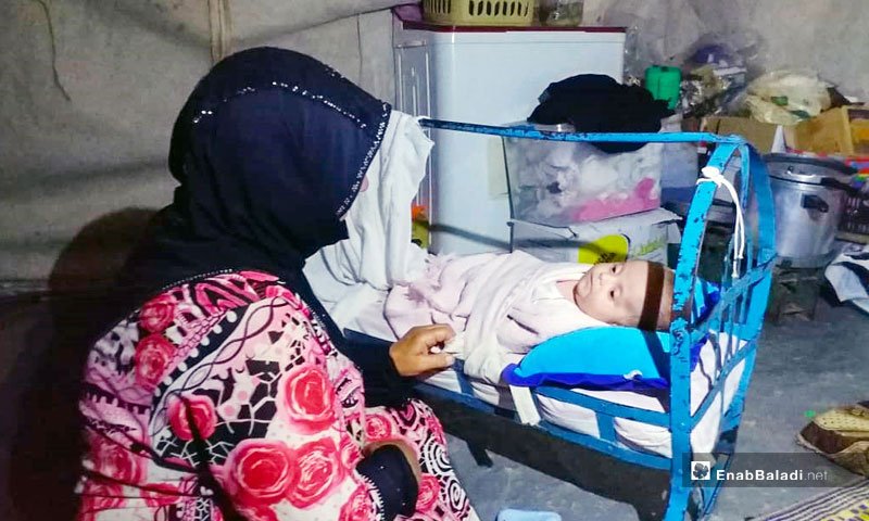 A Syrian mother rocks her baby in the Qalah displacement camp in the northern countryside of Idlib- 11 August 2019 (Enab Baladi)