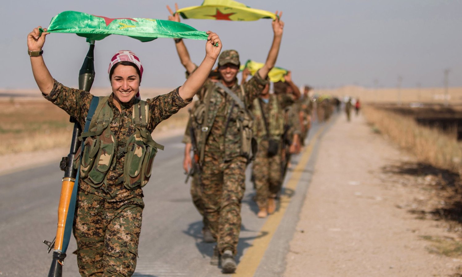 Kurdish fighters waving YPG flags while making victory signs - 2017 (Reuters)