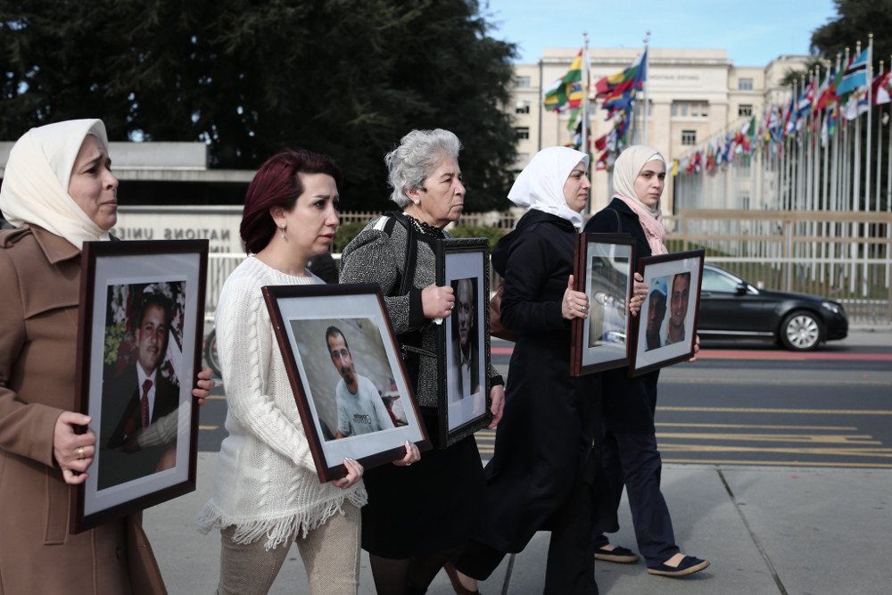 Syrian women holding photos of detained relatives in front of the UN headquarters in Geneva—2017 (Families for Freedom)
