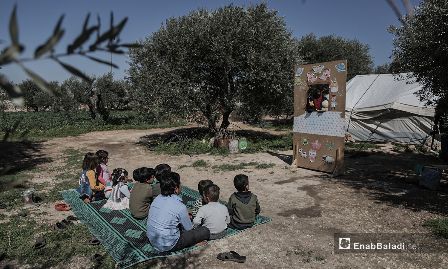 Displaced children watching a puppet show staged by al-Harah theater group in one of the displacement camps near Idlib city - 28 March 2021 (Enab Baladi / Yousef Ghuraibi)
