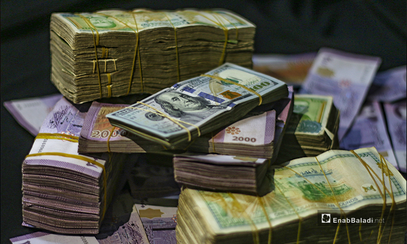 An expressive picture of stacks of USD and SYP banknotes in the city of Idlib- 2 June 2020 (Enab Baladi / Youssef Gharibi)