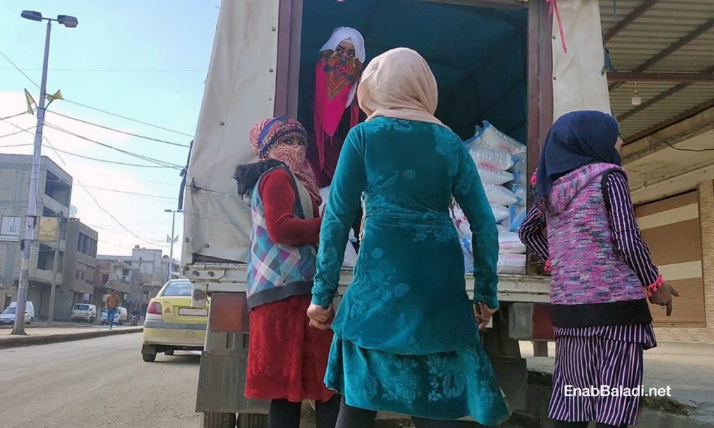 A group of young women unloading a sugar cargo from a truck in the al-Corniche Street in Qamishli city – 20 February 2021 (Enab Baladi/ Majd al-Salem)