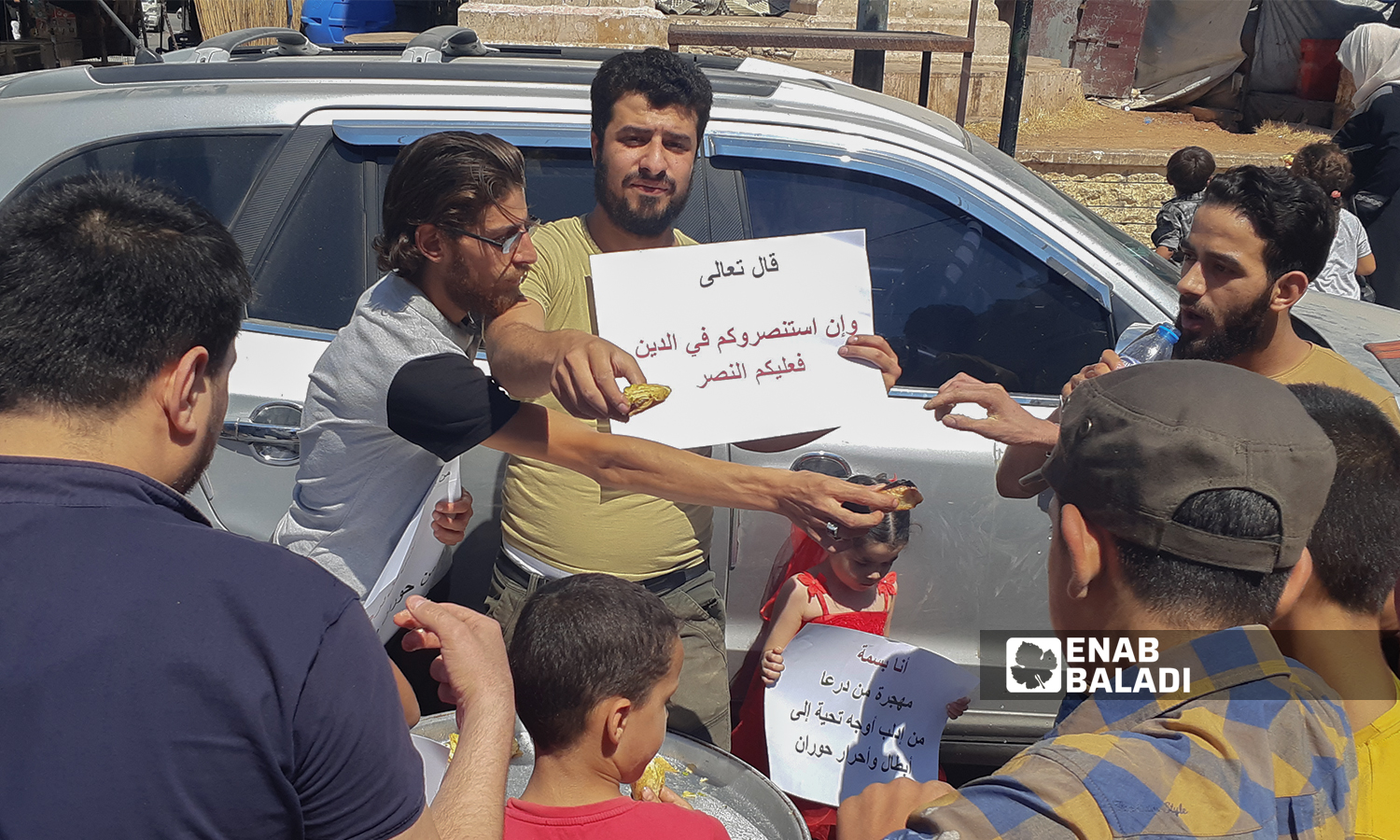 A group of young men carrying banners in solidarity with Daraa residents, and offering sweet desserts after the military checkpoints of the Syrian regime were erected - 29 July 2021 (Enab Baladi-Anas al-Khouli)

