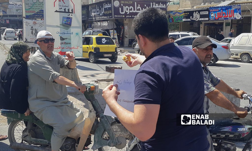 A group of young men carrying banners in solidarity with Daraa residents, and offering sweet desserts after the military checkpoints of the Syrian regime were erected - 29 July 2021 (Enab Baladi-Anas al-Khouli)