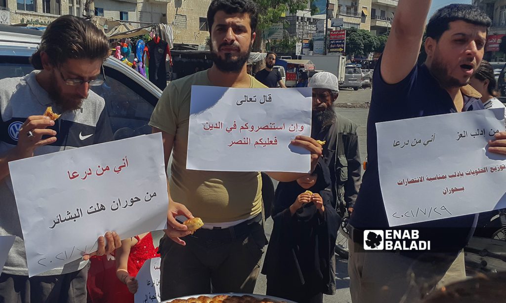 A group of young men carrying banners in solidarity with Daraa residents, and offering sweet desserts after the military checkpoints of the Syrian regime were erected - 29 July 2021 (Enab Baladi-Anas al-Khouli)