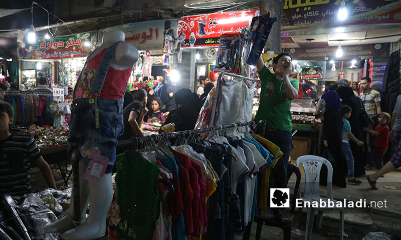 A child selling clothes at a stall in one of Aleppo’s street markets - 4 July 2016 (Enab Baladi)