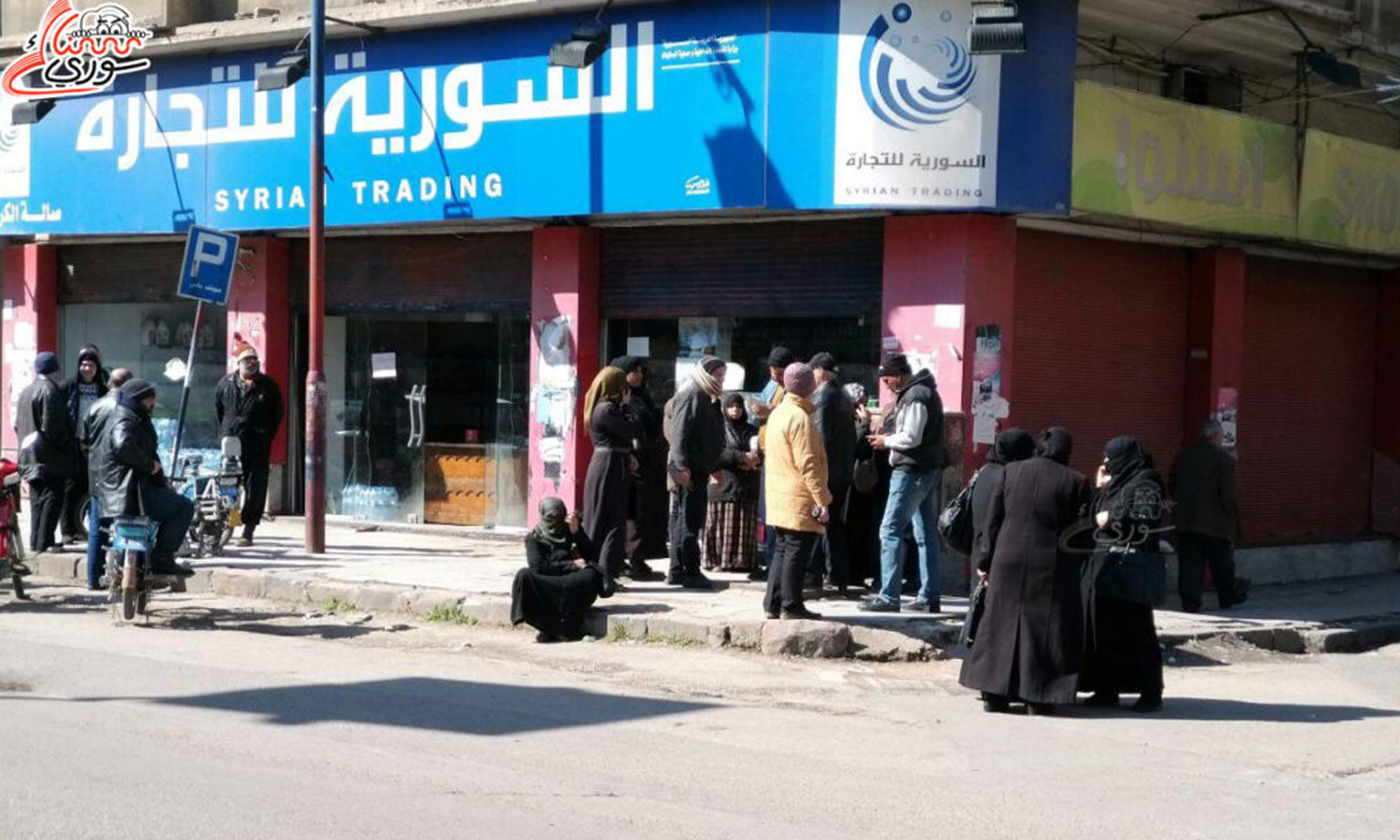 Citizens gather in front of one of the halls of the Syrian Trade Establishment in the city of Homs (Snack Syrian)