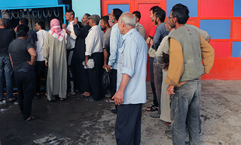 People standing in a queue at an ice blocks making factory amid power outages in al-Hasakah city - May 2021 (North Press Agency)