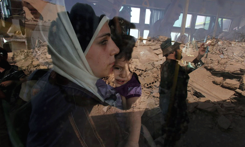 A Syrian woman holding her child while being forced out of Darayya in Damascus’ western Ghouta - 29 December 2016 (AFP)