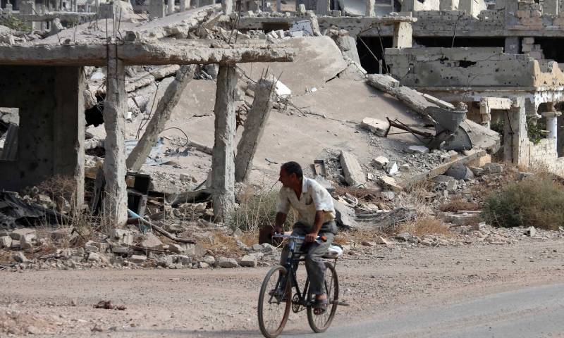 A Syrian man driving a bicycle near destroyed buildings in a neighborhood controlled by opposition factions in Daraa city, southern Syria - 2 October 2018 (AFP / Mohamad Abzed)