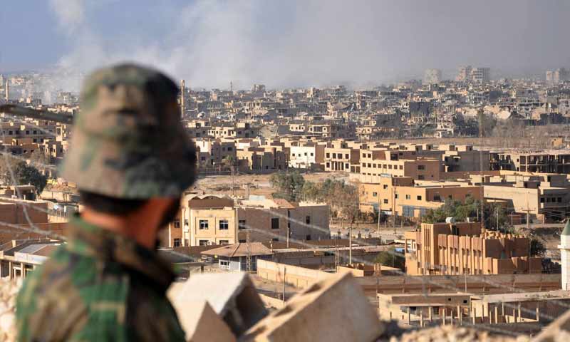 An element of the Syrian regime forces standing on a mountain top overlooking Deir Ezzor city (AFP)