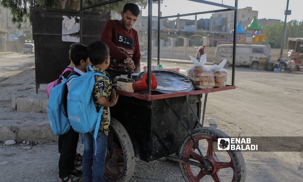 Primary school pupils having bread and salep on their way to school in the morning with the start of the new school year in the northern countryside of Aleppo- Azaz- 22 September 2021(Enab Baladi-Walid Othman)