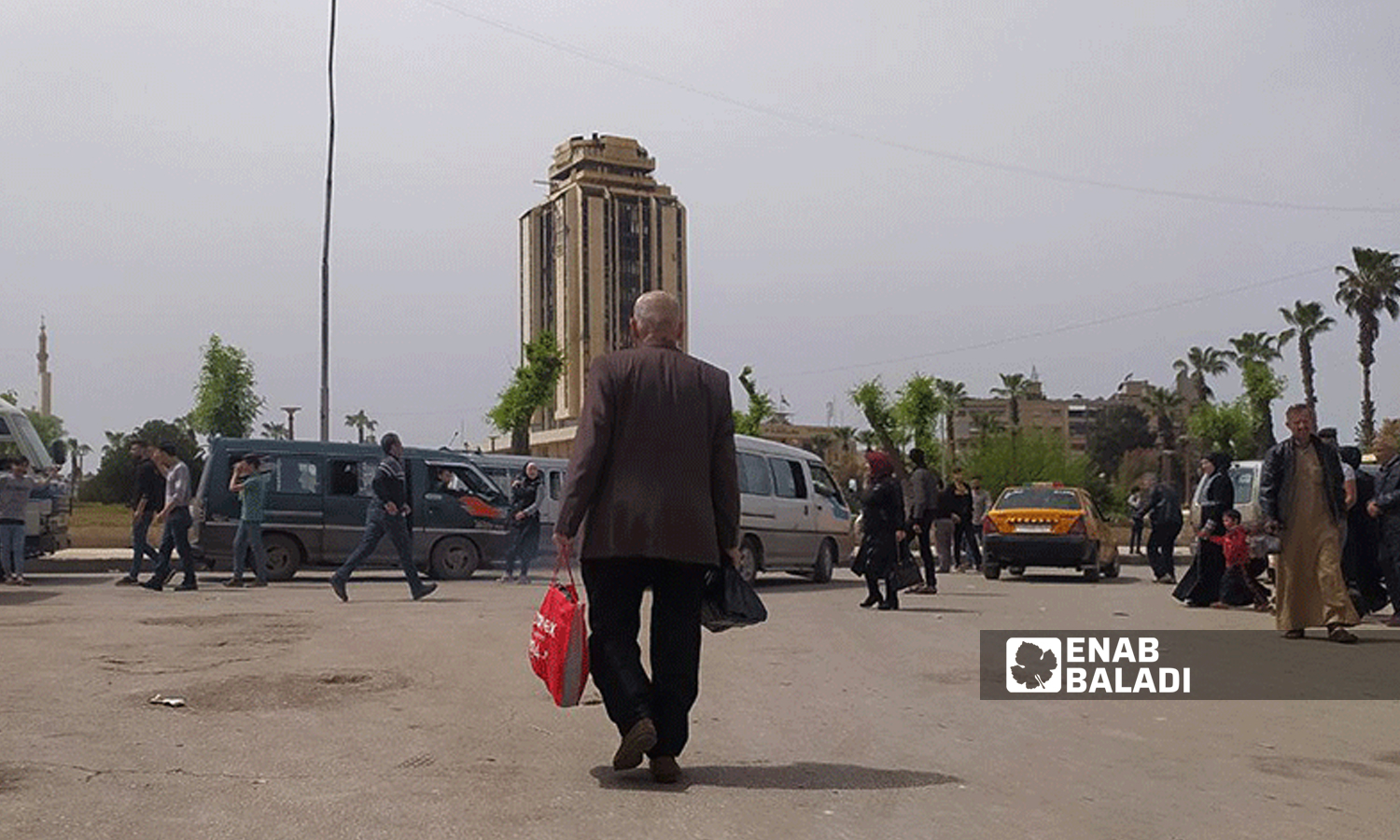 An elderly Syrian man walking the street near the “Municipal Palace” tower in the al-Masharqa neighborhood in northern Aleppo - 17 April 2021 (Enab Baladi / Saber al-Halabi)