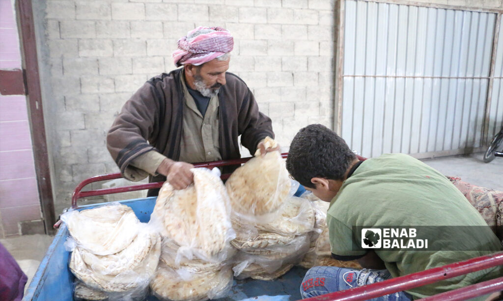 A man arranging bread pundles inside a small truck to transfer them to the selling center in al-Bab city - 8 October 2021 (Enab Baladi - Siraj Mohammed)