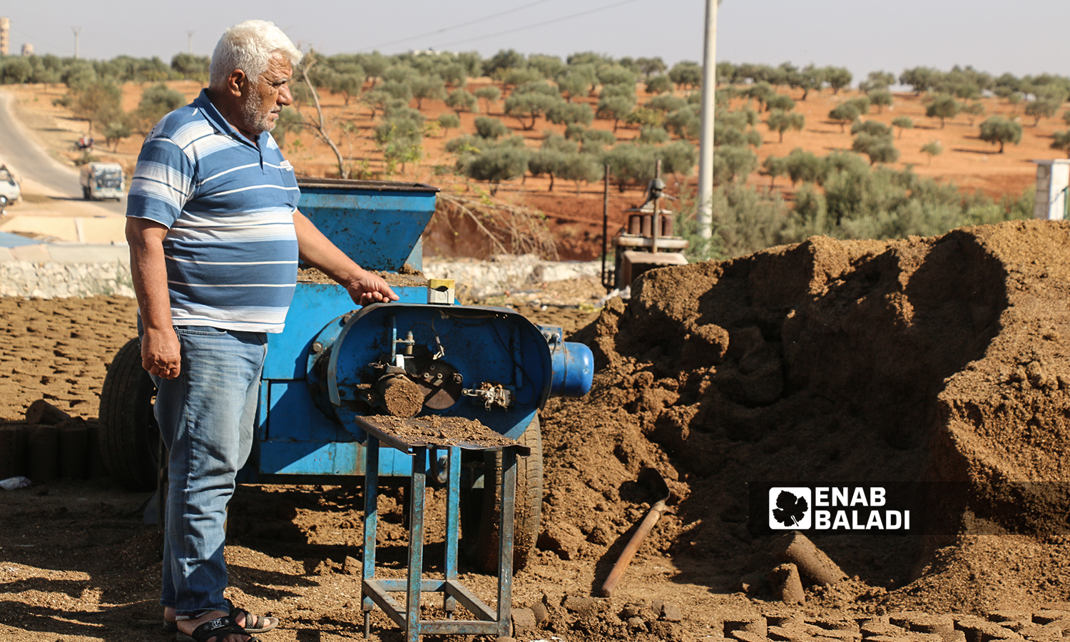 A Syrian worker putting olive residues in a pomace pellet making machine at Maarat al-Ikhwan in the northern Idlib countryside - 18 October 2021 (Enab Baladi/Iyad Abdul Jawad)

