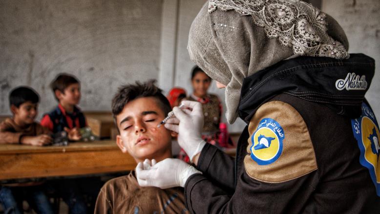 A female volunteer in the Syria Civil Defence (SCD) injecting a child with anti-leishmaniasis drugs - 2021 (Syria Civil Defence)
