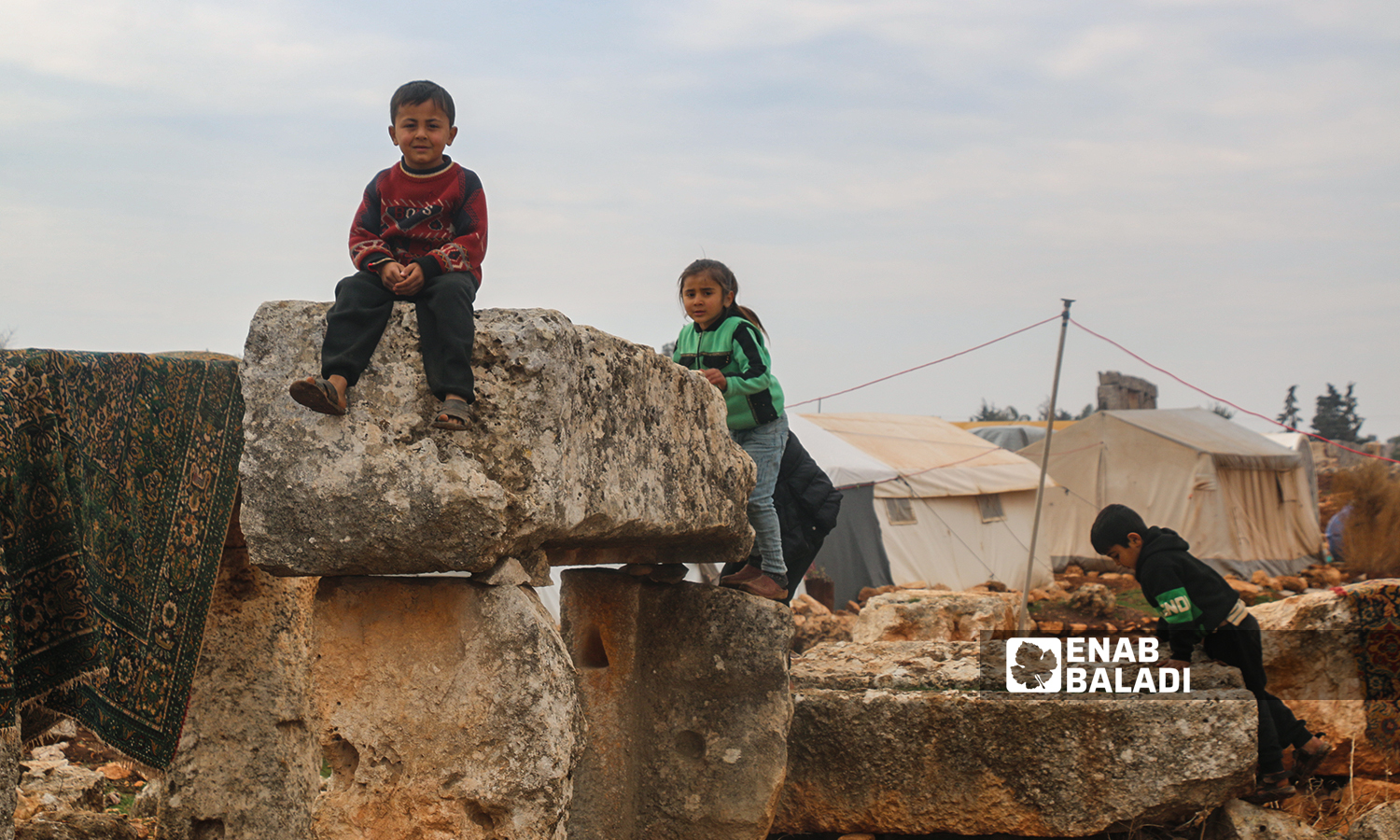 Displaced Syrian children playing near their tents, set up in an archeological site in the ancient Sarjableh area in the northern countryside of Idlib governorate - 22 January 2022 (Enab Baladi / Iyad Abdul Jawad)
