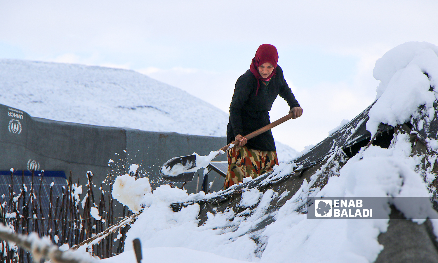 Displaced Syrians clear accumulated snow off the roof of their tents following snowstorms that hit the Sheikh Bilal camp in Rajo area of Afrin district, northern Aleppo - 20 January 2022 (Enab Baladi / Malek al-Habal)