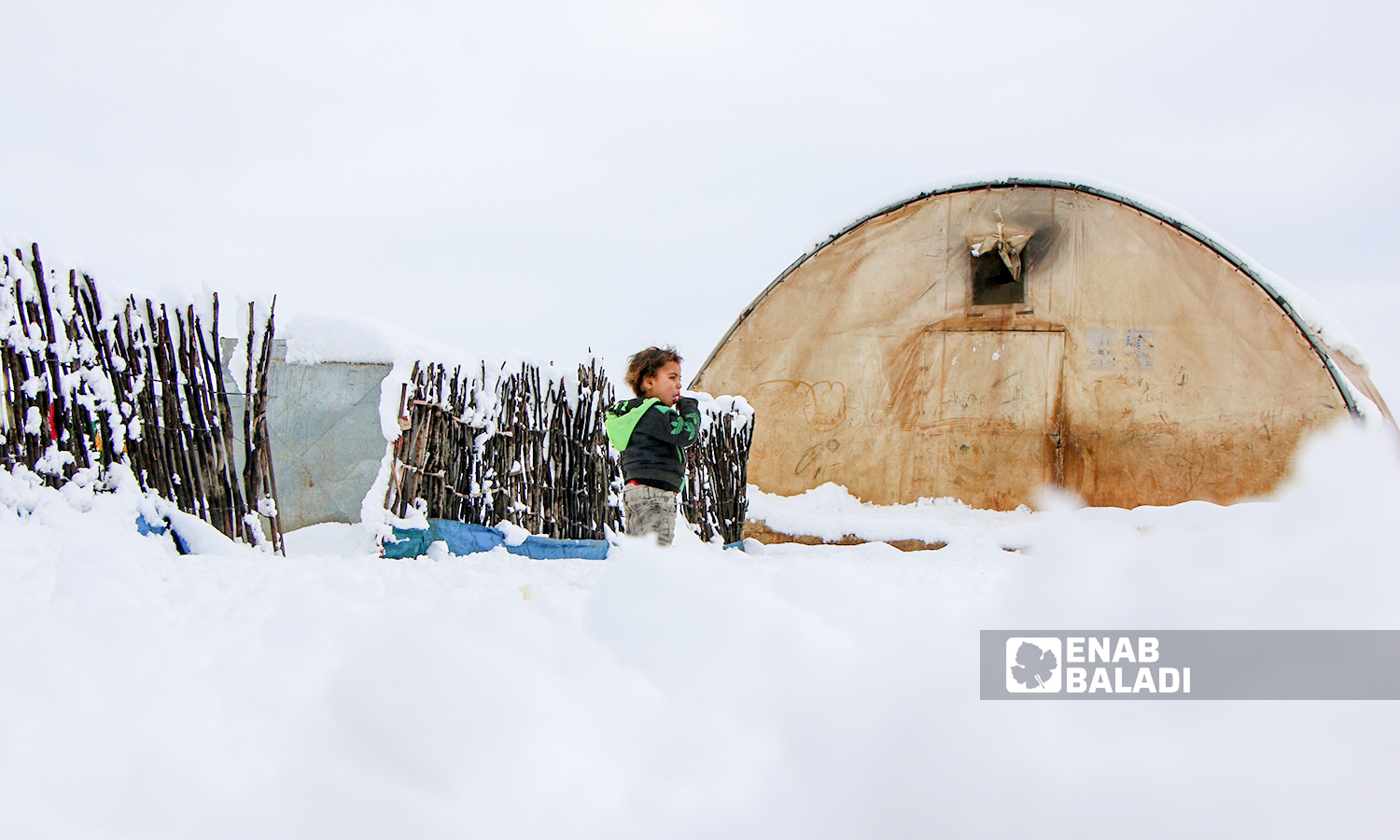 Displaced Syrians clear accumulated snow off the roof of their tents following snowstorms that hit the Sheikh Bilal camp in Rajo area of Afrin district, northern Aleppo - 20 January 2022 (Enab Baladi / Malek al-Habal)