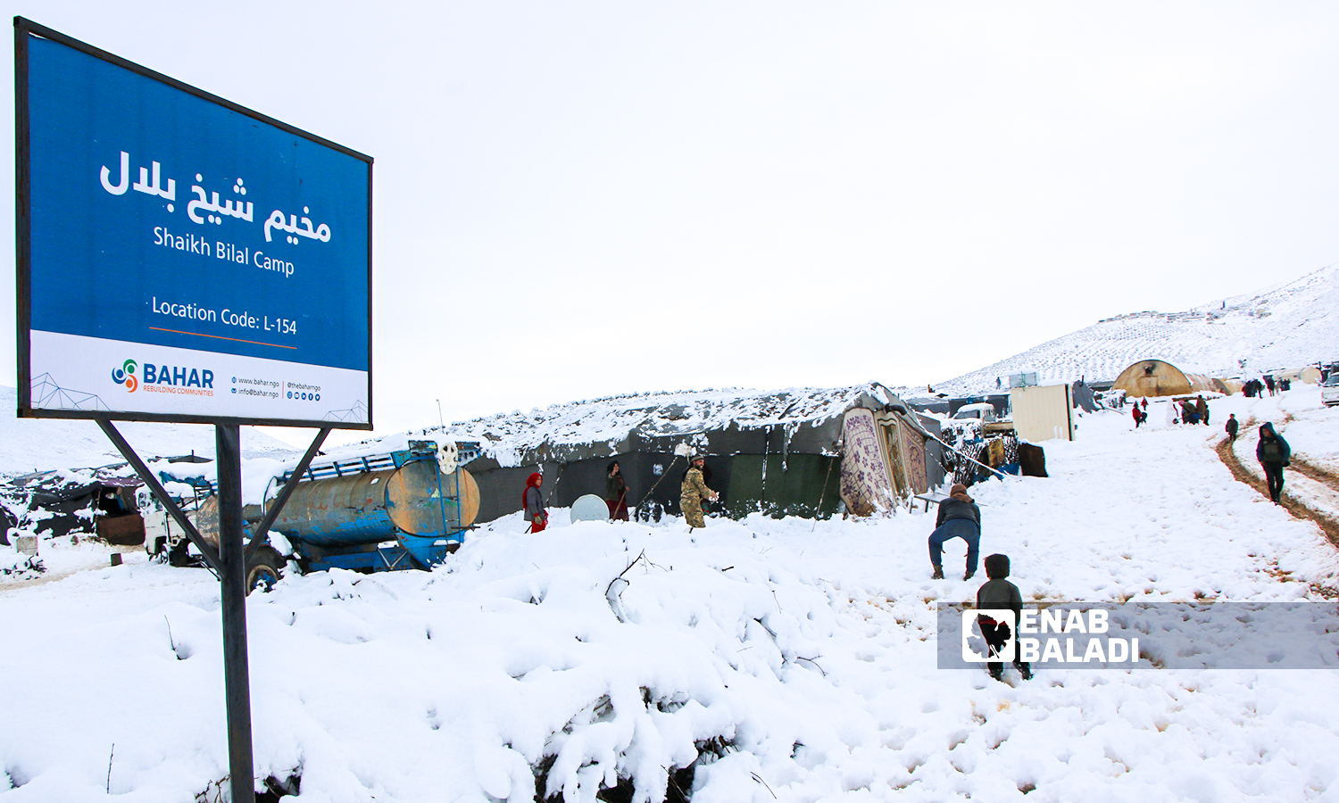 Displaced Syrians clear accumulated snow off the roof of their tents following snowstorms that hit the Sheikh Bilal camp in Rajo area of Afrin district, northern Aleppo - 20 January 2022 (Enab Baladi / Malek al-Habal)