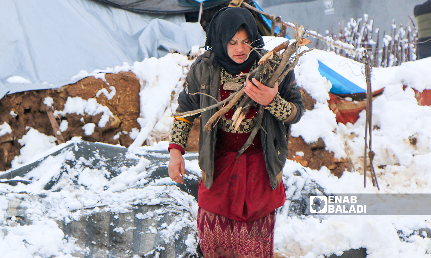 Displaced Syrians clear accumulated snow off the roof of their tents following snowstorms that hit the Sheikh Bilal camp in Rajo area of Afrin district, northern Aleppo - 20 January 2022 (Enab Baladi / Malek al-Habal)