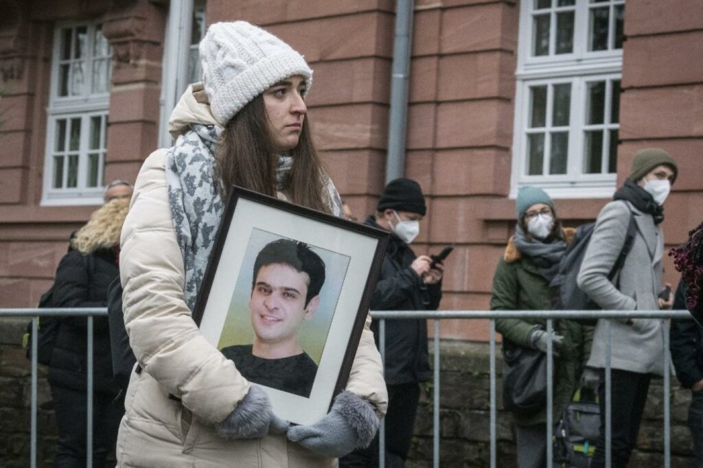 Syrian activist Sama Mahmoud carrying a picture of her uncle, Hayyan Mahmoud, who is detained in the Syrian regime’s prisons, in front of the Koblenz court in wait for the verdict against Anwar Raslan - 13 January 2022 (AFP)