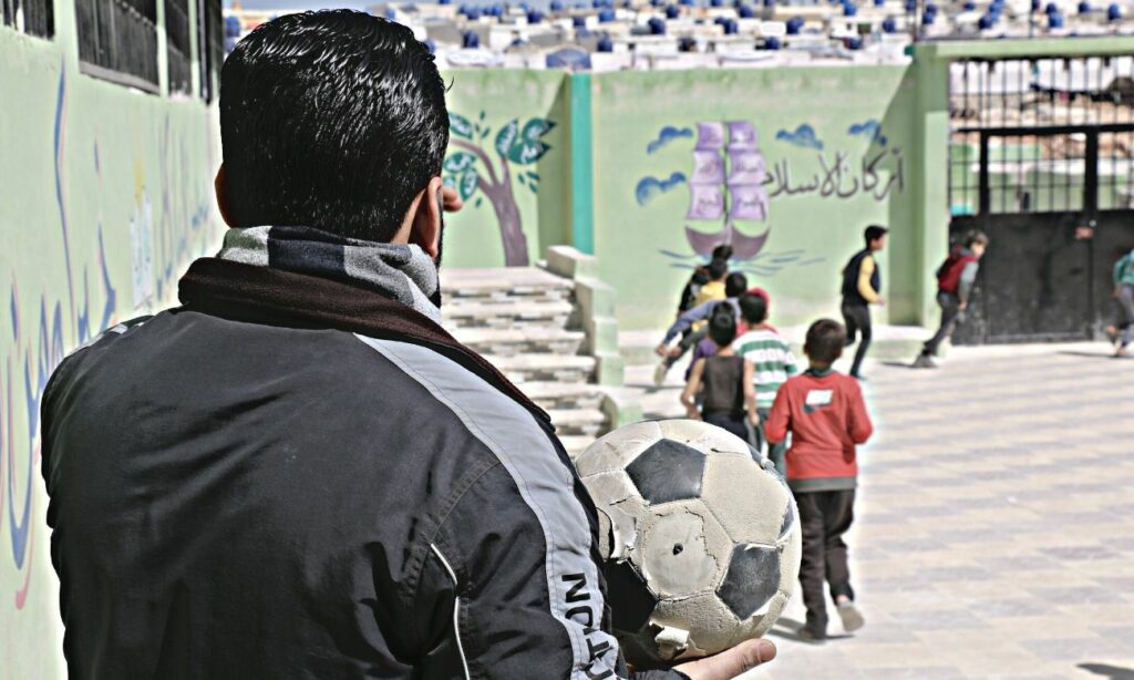 A teacher holding a ball in a schoolyard in Idlib countryside - 9 April 2022 (Enab Baladi / Iyad Abdul Jawad)