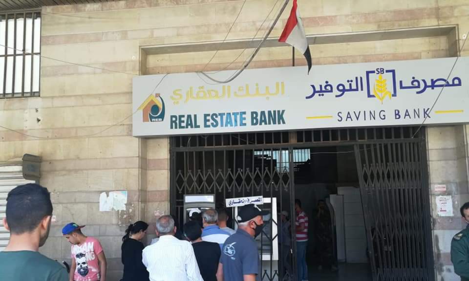 People queuing at the joint ATMs of Savings and Real Estate banks in Homs city (Local al-Khabar TV)