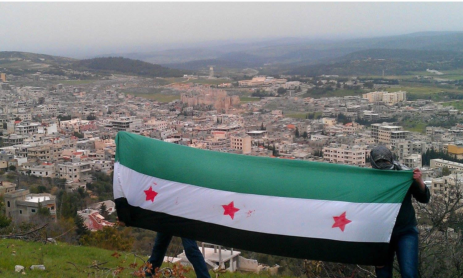 Opponents of the regime raise the flag of the Syrian revolution in the Ismaili-majority city of Masyaf in the northern Hama countryside (Masyaf Coordination Facebook page)