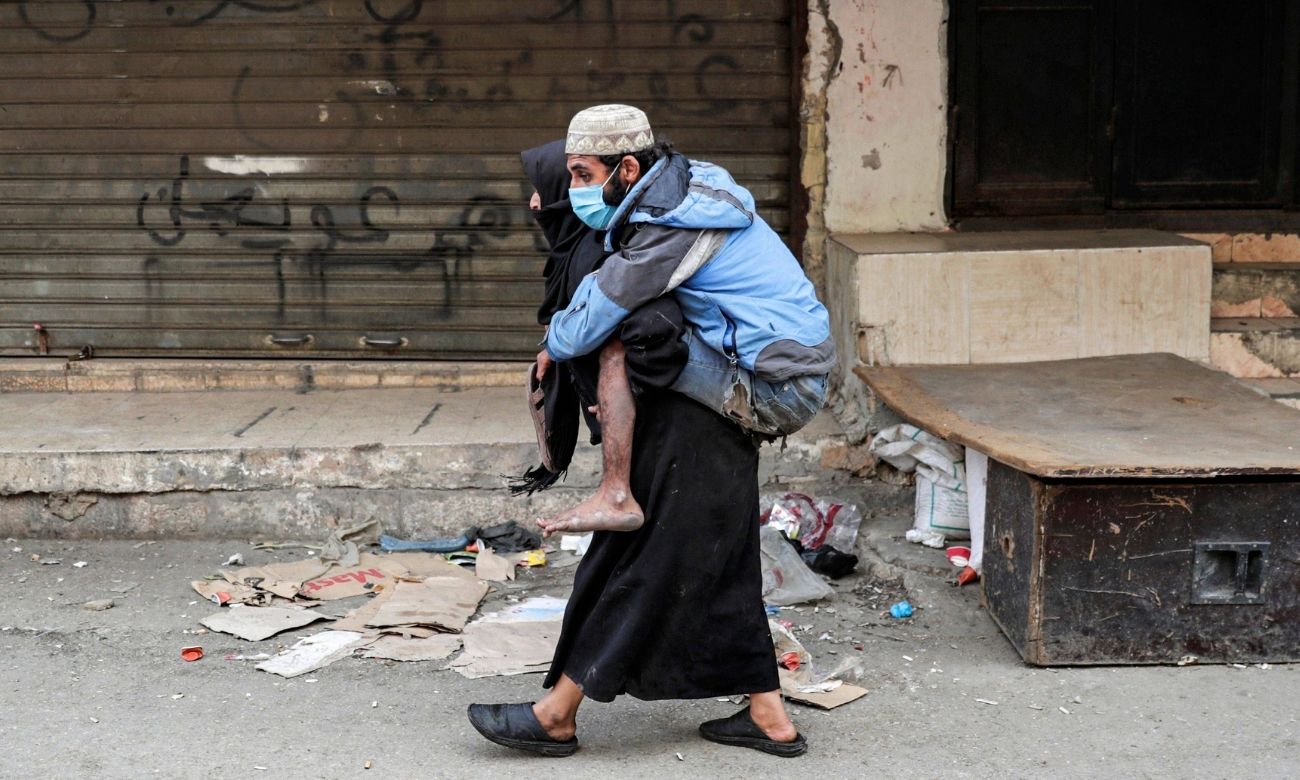 A woman carries a man with special needs in the Sabra refugee camp in Lebanon - 5 April 2020 (AFP)
