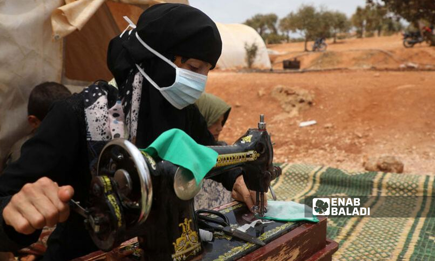 A woman sewing clothes in the IDP camp of Kelli in northern Idlib region (edited by Enab Baladi)