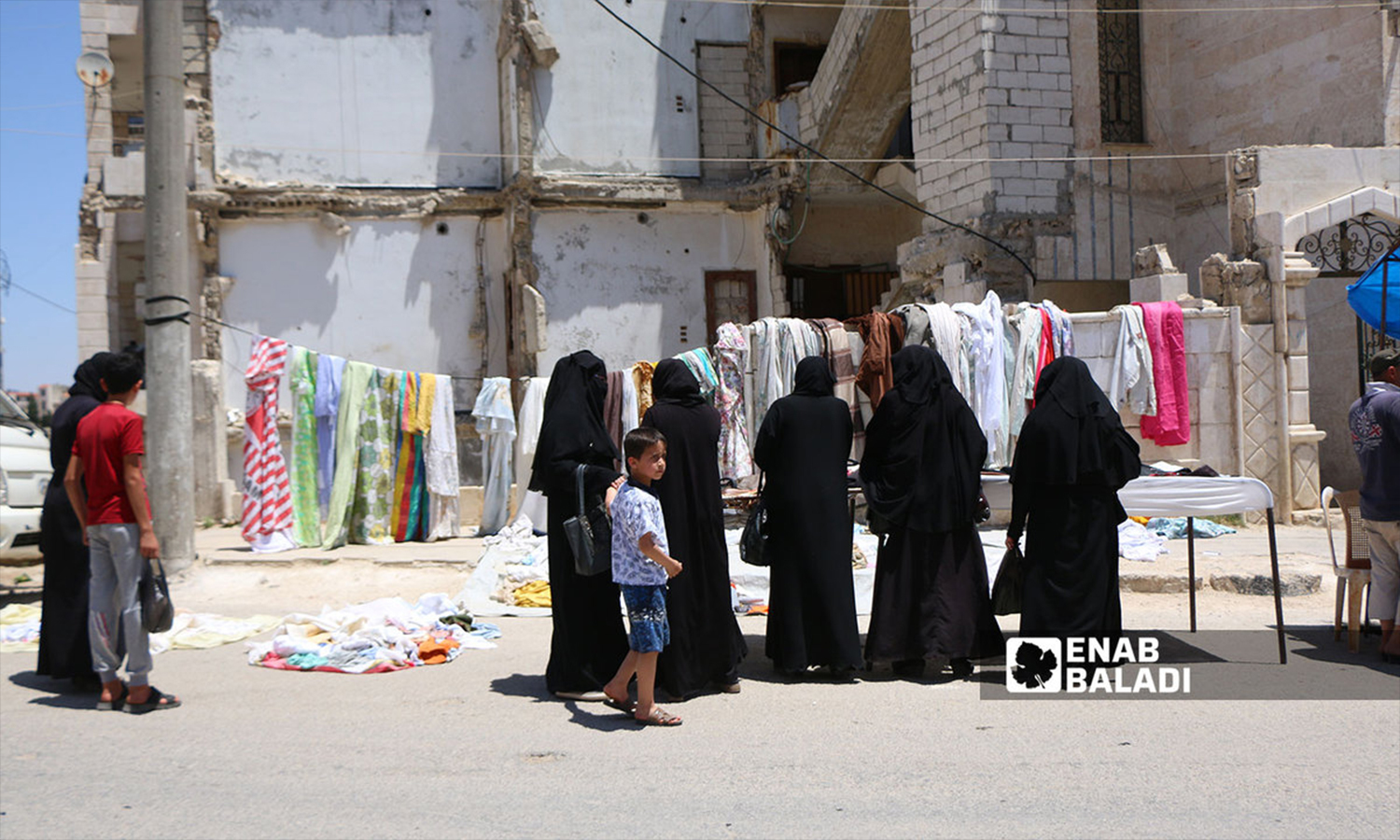 Syrian women in front of a clothes stand in northern Idlib city - 21 June 2022 (Enab Baladi)