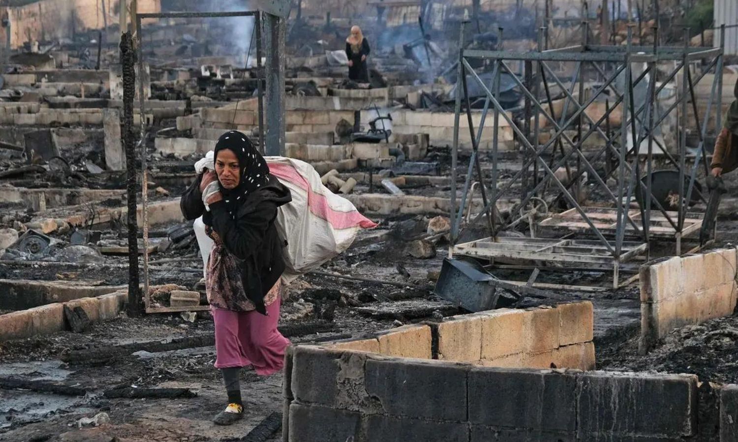 Syrian refugees retrieve their belongings from a camp that was set on fire in the town of Behnin in northern Lebanon - 27 December 2020 (AFP)