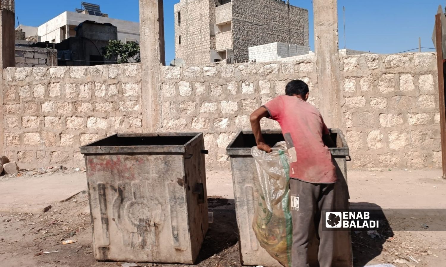 A young man scavenges trash in the city of al-Dana, north of Idlib, August 2022 (Enab Baladi / Huda al-Kulaib)