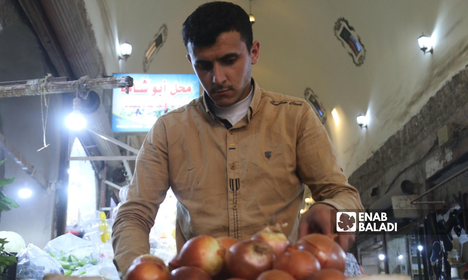 A man buys onions in the covered market of Azaz city in Aleppo’s northern countryside - 02 September 2022 (Enab Baladi/Dayan Junpaz)
