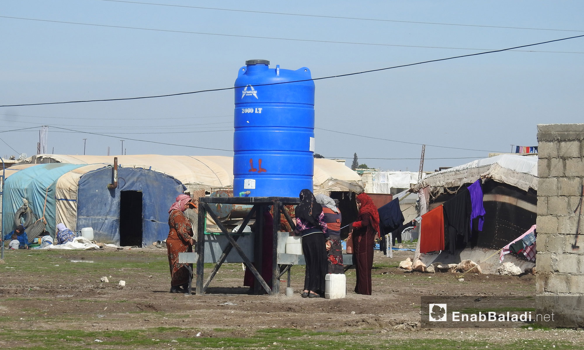 IDP women gather around a water tank in al-Marj camp in the northern countryside of Aleppo – 19 February 2018 (Enab Baladi)