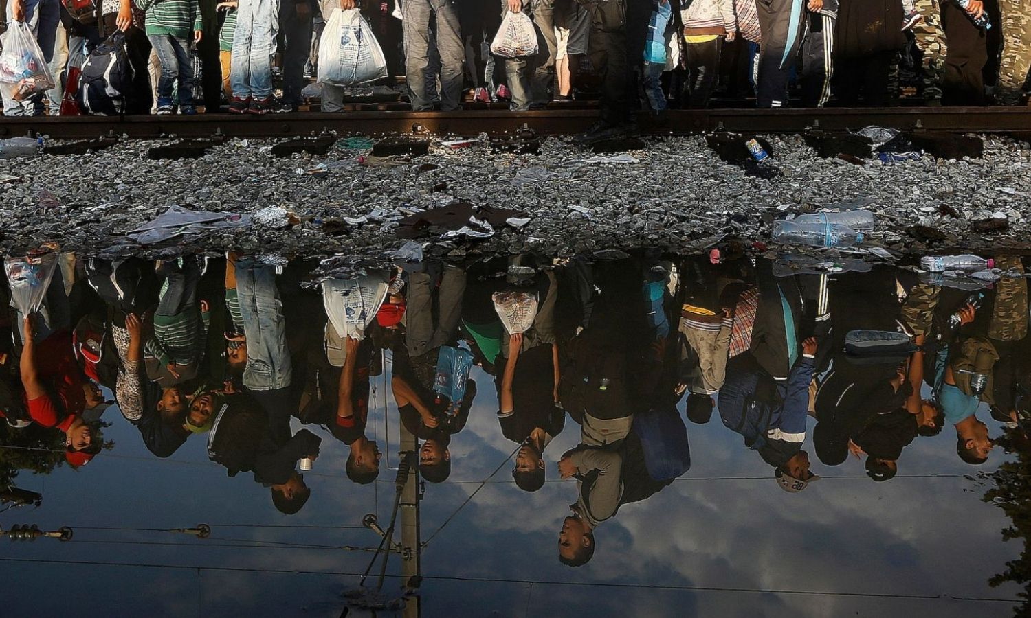 Syrian refugees on the Greek border, their bodies reflected in the water, while waiting to enter the Macedonian border in September 2015 (Reuters)