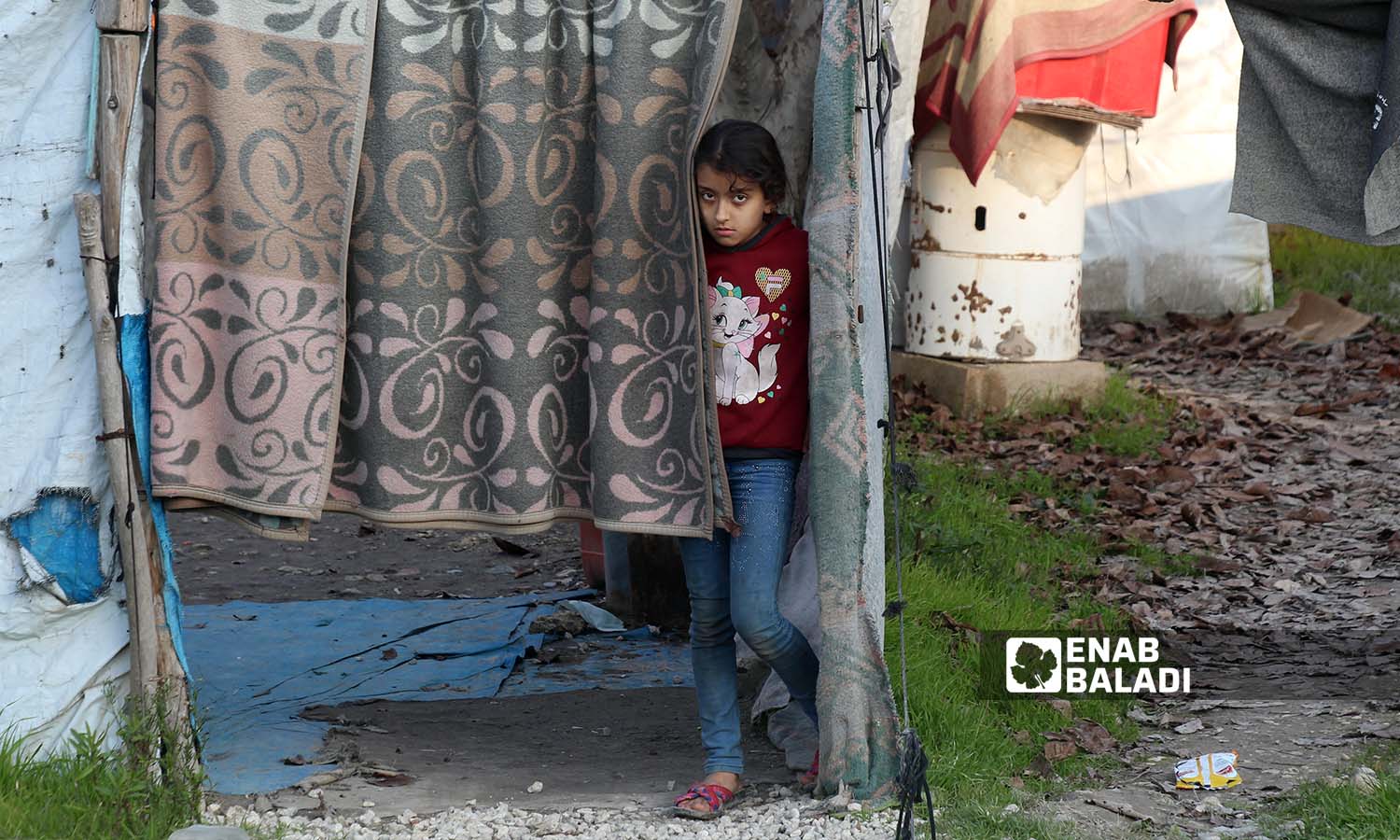 A child stands near the door of her tent in the Kherbet al-Jouz camp in Idlib countryside near the Turkish borders - 23 December 2022 (Enab Baladi / Iyad Abdul Jawad)
