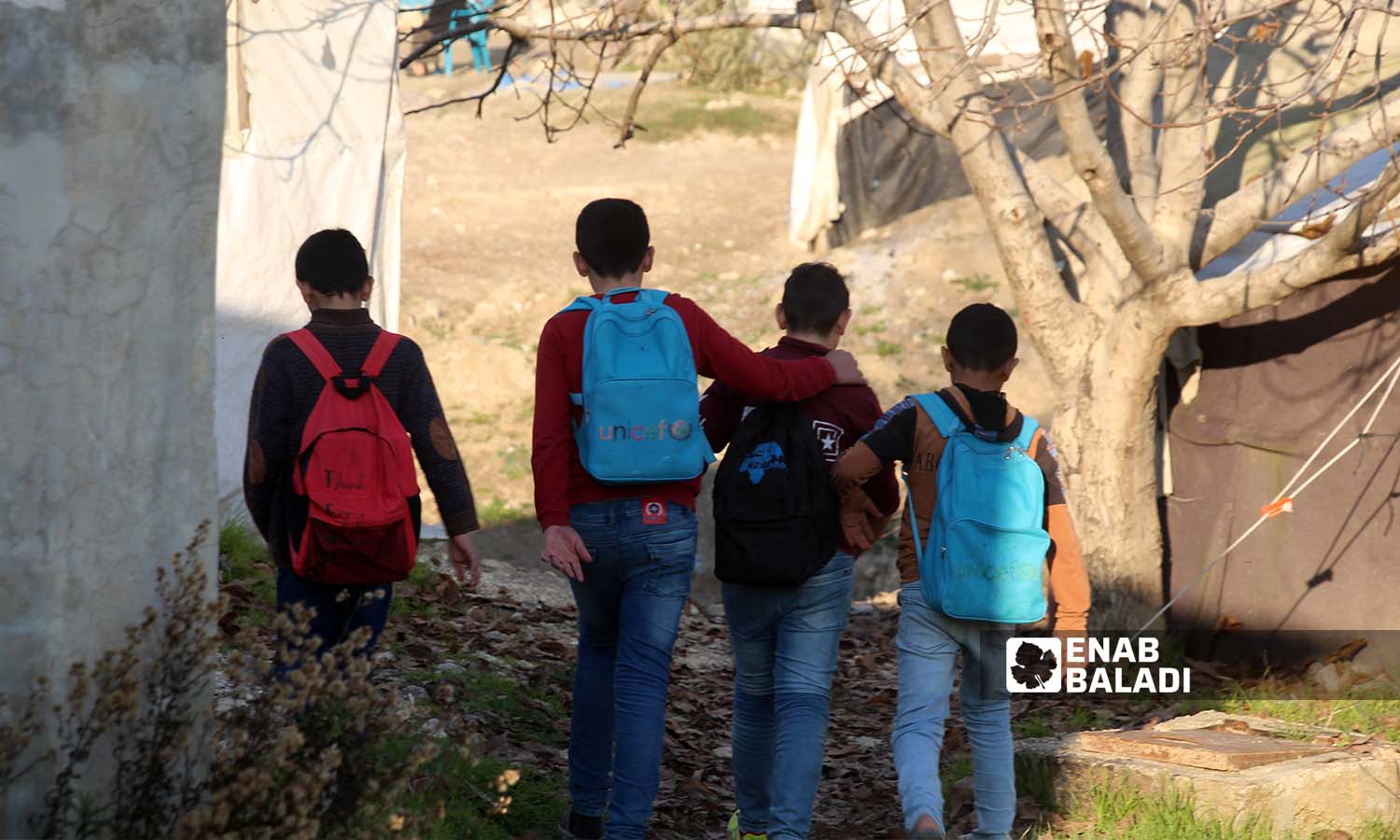 Children with school backpacks on their way to their tents in the Kherbet al-Jouz camp in Idlib countryside near the Turkish borders - 23 December 2022 (Enab Baladi / Iyad Abdul Jawad)
