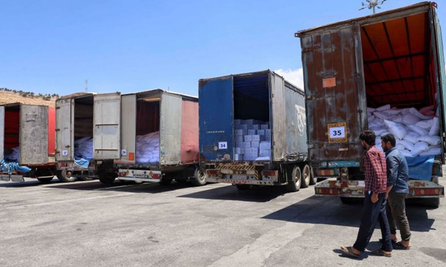 Workers unloading a United Nations aid convoy truck after it entered Syria through the Bab al-Hawa border crossing with Turkey - 28 July 2022 (Omar Haj Kadour - AFP)
